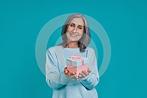 Mature beautiful woman looking at camera and holding gift box