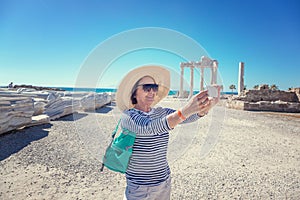 Mature beautiful woman traveler takes pictures on mobile phone.