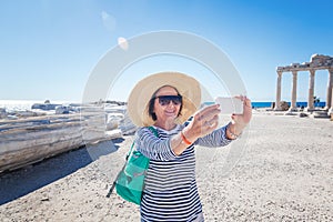 Mature beautiful woman traveler takes pictures on mobile phone.