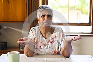 A mature biracial woman looks puzzled at home on a video call