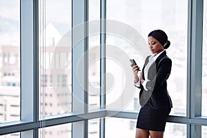 Mature black business woman texting while standing