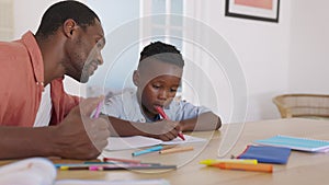 Mature black father helping son with homework
