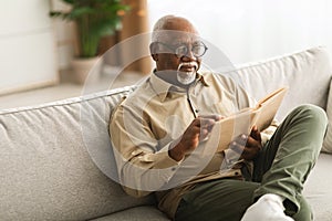 Mature Black Man Reading A Book Relaxing Sitting At Home