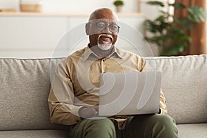 Mature Black Man Using Laptop Smiling To Camera At Home