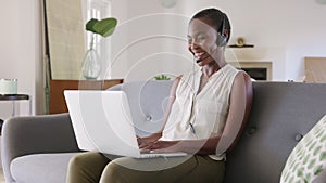 Mature black woman using laptop for video call while working from home