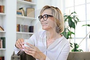 Mature blond woman in couch having a tea or coffee