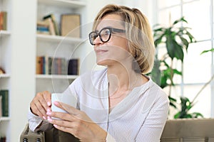 Mature blond woman in couch having a tea or coffee