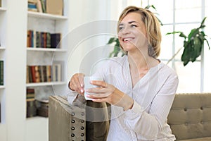 Mature blond woman in couch having a tea or coffee