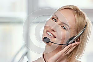 Mature blond woman holding headset.