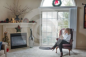 Mature Blond Woman Reading Card by Window