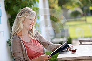 Mature blond woman reading and drinking coffee