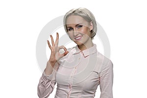 Mature blond woman is showing ok gesture.