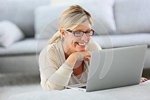 Mature blond woman using laptop at home