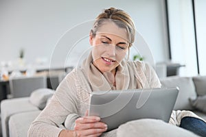 Mature blond woman websurfing on tablet photo