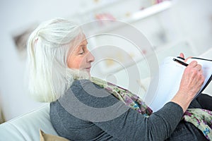 Mature blond woman writing on notebook