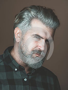 Mature blonde bearded guy with trendy hairdo in casual shirt smiling and looking in camera. Close up portrait of a very