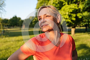 Mature blonde woman portrait in park on sunset summer day