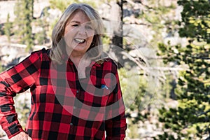 A mature blonde woman wearing a flannel shirt red and black poses for a portrait in the Eastern Sierra Nevada