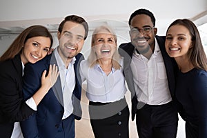 Mature boss company staff members hugging laughing looking at camera