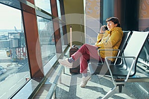 Mature brunette woman sitting in the airport lounge and speaks on the phone