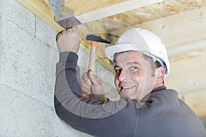 mature builder using hammer on roof joist