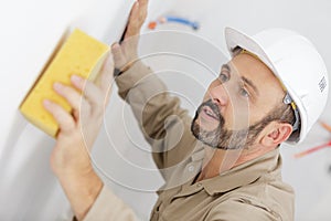 Mature builder using sponge on wall