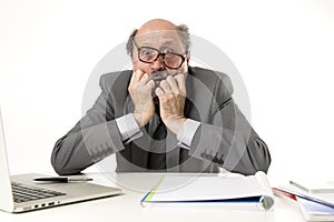 Mature business man with bald head on his 60s working stressed and frustrated at office computer laptop desk looking desperate