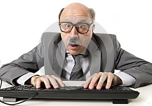 Mature business man with bald head on his 60s working stressed and surprised at office computer laptop desk looking in shock