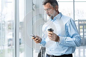 Mature business man in formal clothing using mobile phone. Serious businessman using smartphone at work. Manager in suit