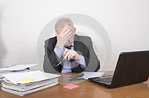 Mature business man in an office setting looking tired