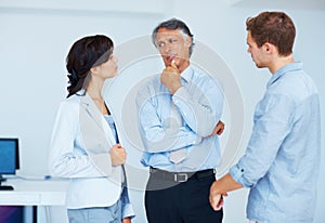 Mature business man sharing views with colleagues. Portrait of young business people listening to their mature leader in