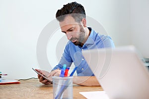 Mature business man sitting at his desk using digital tablet
