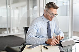 Mature business man working on digital tablet in office