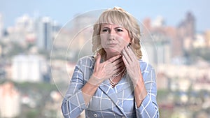 Mature business woman is coughing on blurred background.