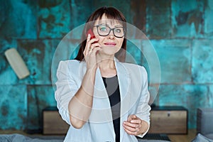 Mature business woman talking on mobile phone in office