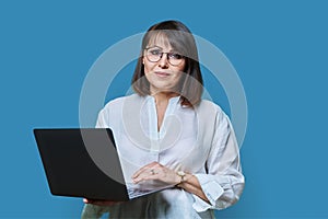 Mature business woman using laptop on blue background