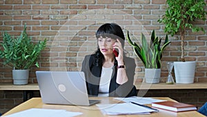 Mature business woman in workplace, sitting at desk, talking on phone