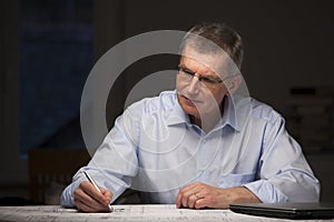 Mature businessman or architect working in a dark room at home