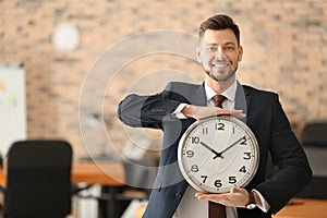 Mature businessman with clock in office. Time management concept