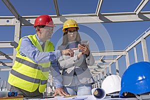 Mature Businessman and Female Architect on Building Site Checking Plans