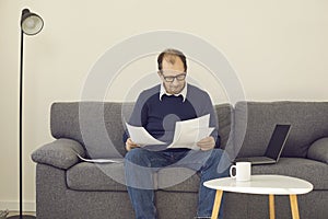 Mature businessman freelancer working with paper documents in home office