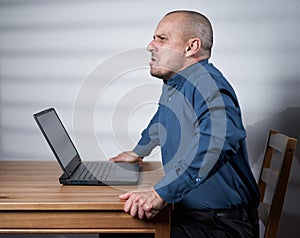 Mature businessman with laptop at his desk, hostile attitude