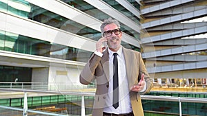 Mature businessman laughing during a phone call, in a modern urban landscape