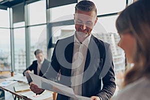 Mature businessman manager is holding documents consulting client at office meeting