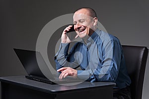 Mature businessman multitasking with phone and laptop