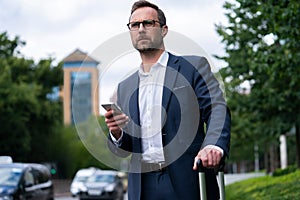 Mature Businessman Ordering Taxi Using Mobile Phone App photo