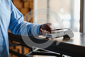 Mature businessman paying with contactless credit card with NFC technology.