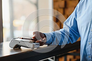 Mature businessman paying with contactless credit card with NFC technology.