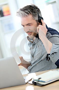 Mature businessman teleworking on laptop