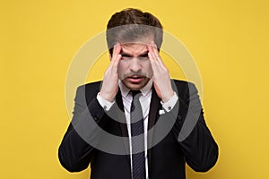 Mature businessman touching head feeling headache looking down unhappy